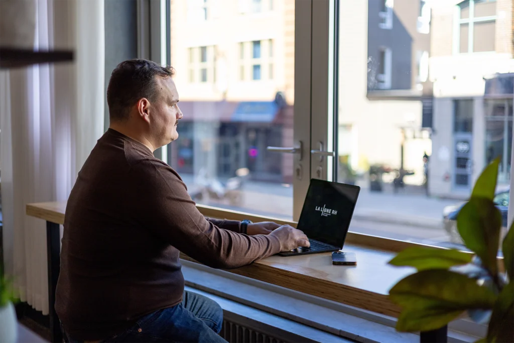 Jean-Christophe Chartrand Gauthier travaille à l’ordinateur devant une fenêtre